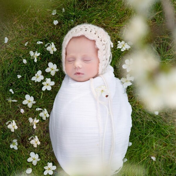 Boho baby lying in nature and flowers