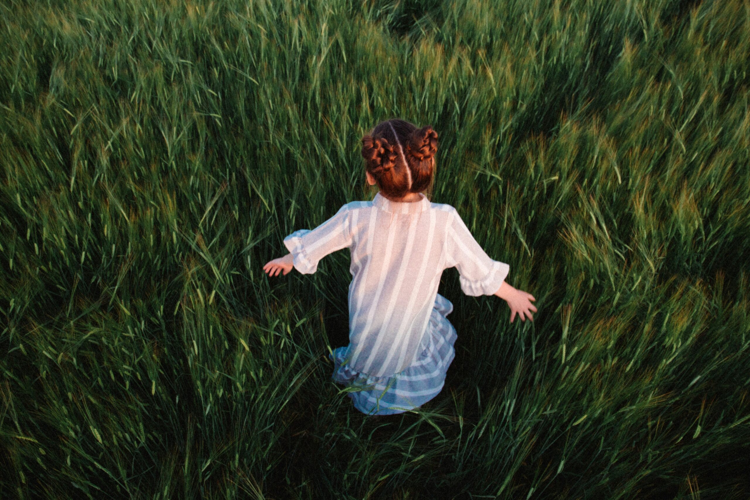 Whimsical baby girl running through a field